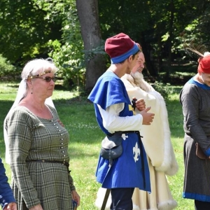 Grupa kobiet i mężczyzn ubranych w sredniowieczne stroje stoi i rozmawia.