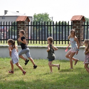 Grupa dzieci biegnie po trawie.