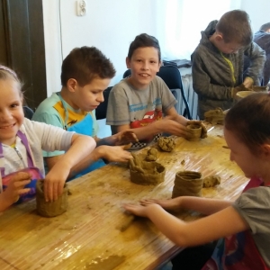 Uśmiechnięta grupa dzieci lepi z gliny  wazoniki.
