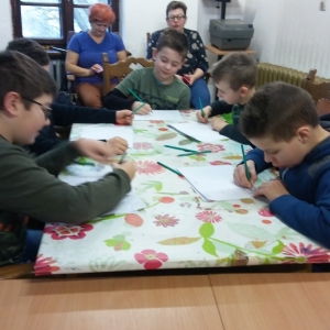  Ferie zimowe 2019 Grupa dzieci siedzi przy stolikach i rysuje na białych kartkach.