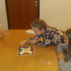 Trzy małe dziewczynki układaja kolorowe pionki na planszy.